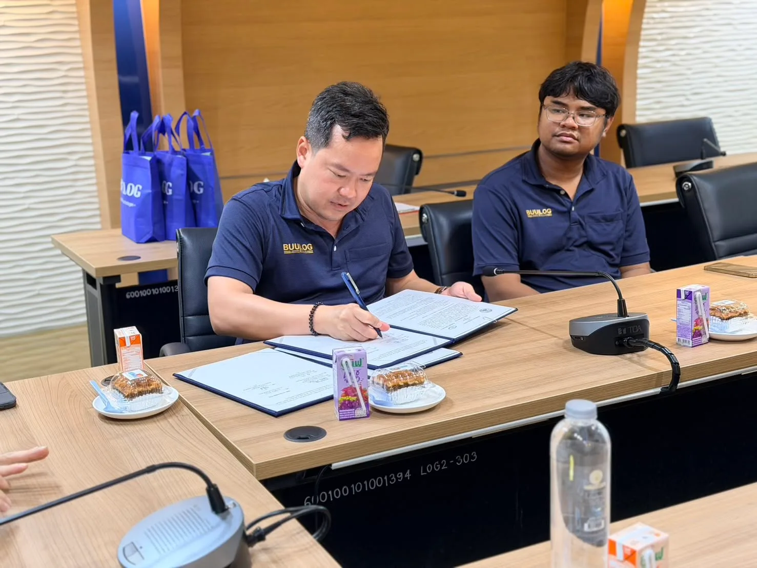 A representative of the Faculty of Logistics signs the MOU with a colleague beside him